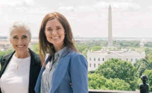 Two women stand smiling in front of the White House, with the Washington Monument and Jefferson Memorial visible in the background on a sunny day, celebrating their Pro-Life Legacy.