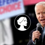 A man with white hair speaks into a microphone, raising his fist. Behind him, blurred signs reading DEFEND CHOICE are visible—a circular icon of a woman's profile is overlaid, hinting at Biden Admin and Planned Parenthood involvement.