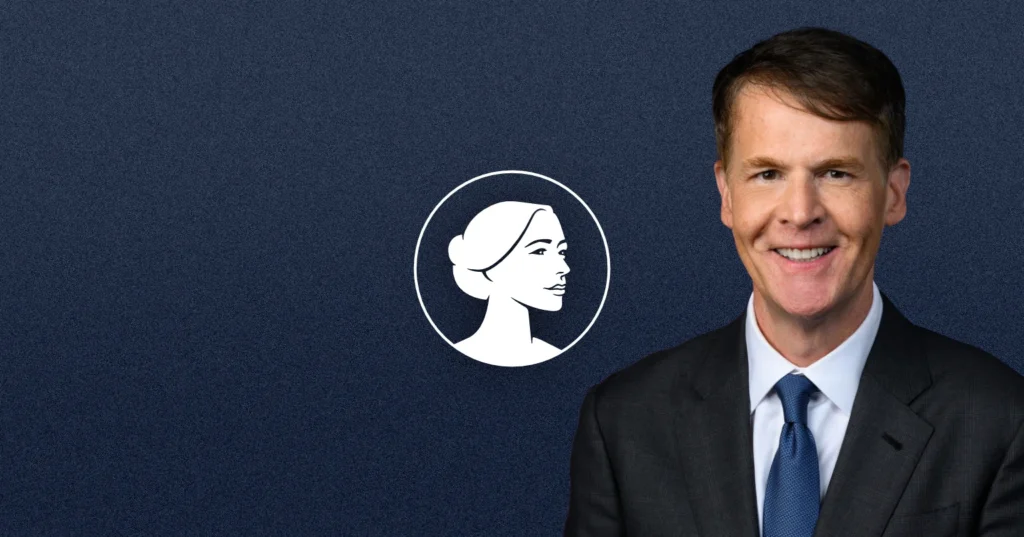 A man in a dark suit and blue tie smiles in front of a dark blue background featuring a white icon of a woman's profile in a circle, supporting Jefferson Shreve's Pro-Life stance.