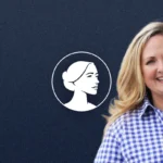 A smiling woman with long blonde hair, wearing a blue and white checkered shirt, stands in front of a dark blue background featuring a white outlined profile of a woman’s face in a circle—Tricia Pridemore, GA-11’s Pro-Life advocate.