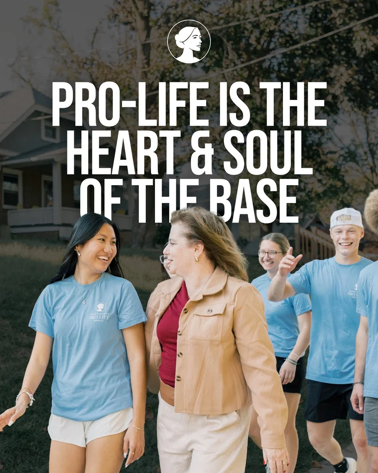 A group of smiling people, some wearing blue pro-life shirts, walk outside near a house. Large white text above reads, Pro-life is the heart & soul of the base.