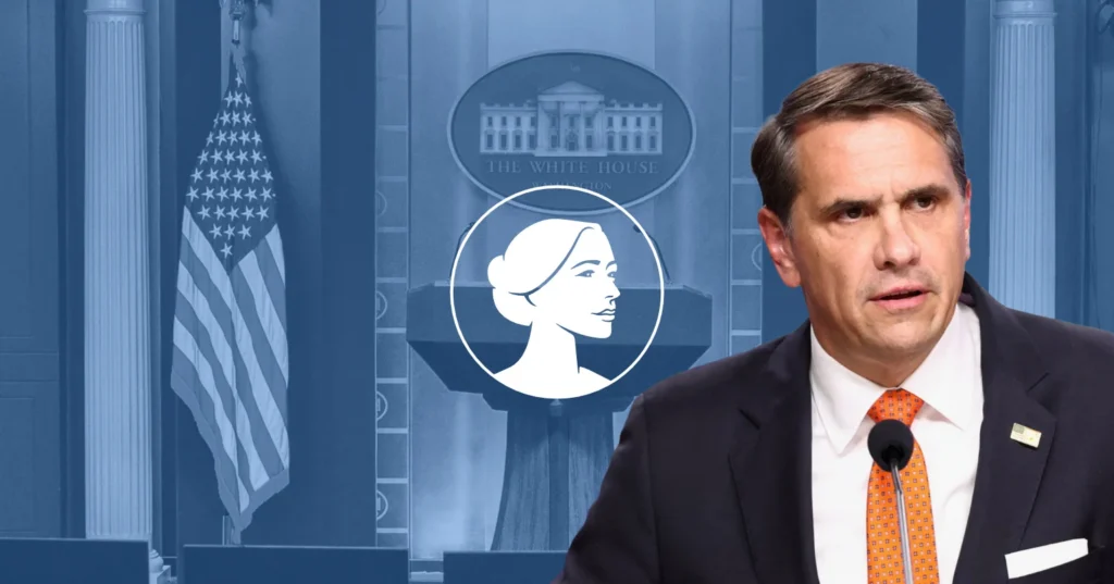 A man in a suit speaks at a podium with a microphone. Behind him are the American flag, a White House emblem, and an illustrated profile of a woman on a blue backdrop, as he addresses the abortion drug lawsuit supported by pro-life groups.