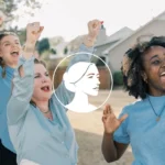 A group of women outdoors cheer and raise their fists, smiling excitedly. Wearing blue shirts emblazoned with a white logo of a woman’s profile centered over the image, these Student Canvassing volunteers radiate energy as they connect with Battleground Voters. Houses are visible in the background, underscoring their commitment to grassroots engagement.