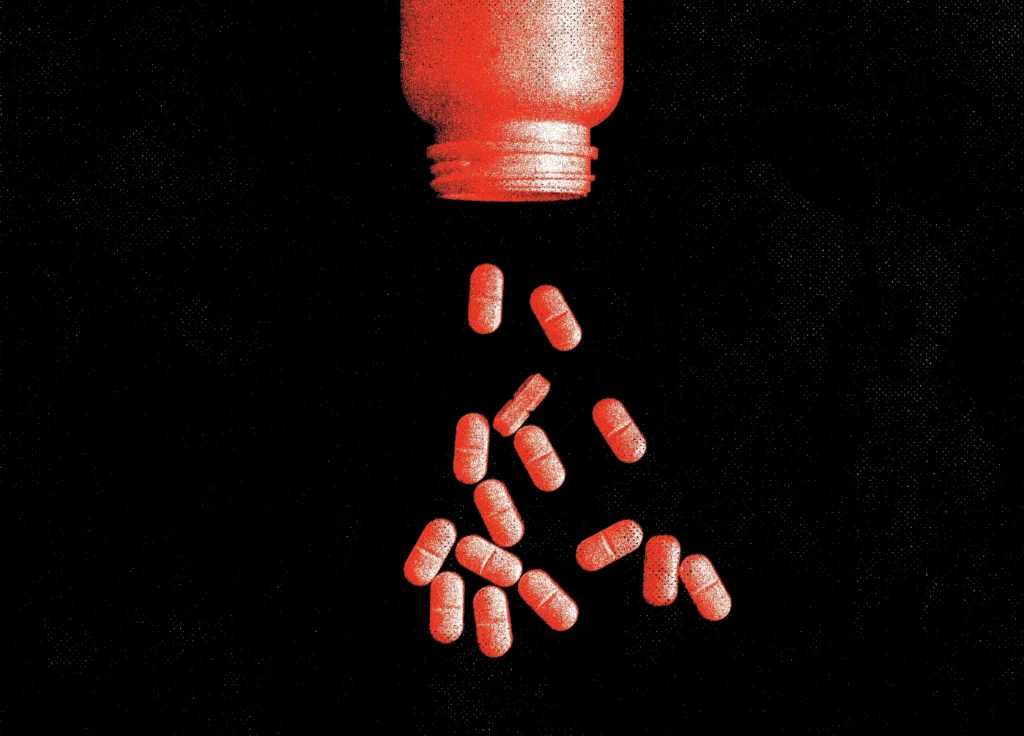 Red capsules, possibly abortion drugs, spilling from an overturned pill bottle against a black background.